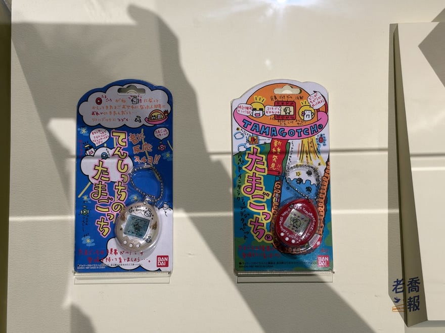 兩盒 1997 年的電子雞（塔麻可吉）原包裝：左邊藍色是天使版，右邊紅色寫著「新種發見」