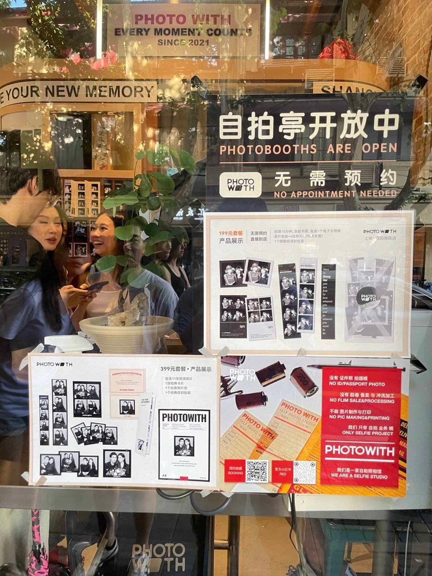 PhotoWith 上海襄陽南路店門市玻璃上的產品展示板，199 元與 399 元套餐的樣張都是黑白照