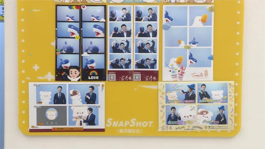 黃色 Snapshot 聯名限定店牆面上貼著多組拍貼成品，有穿西裝的人與小熊、鯊魚、白鵝等角色合成的照片