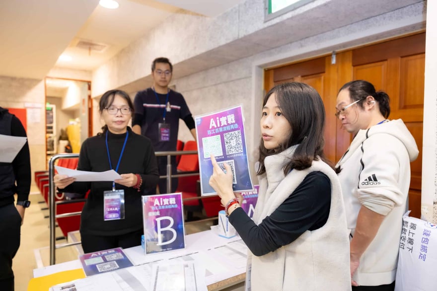 A woman at a conference booth demonstrating AI technology with QR codes, surrounded by attendees and staff, promoting AI-related services and innovations at an event.