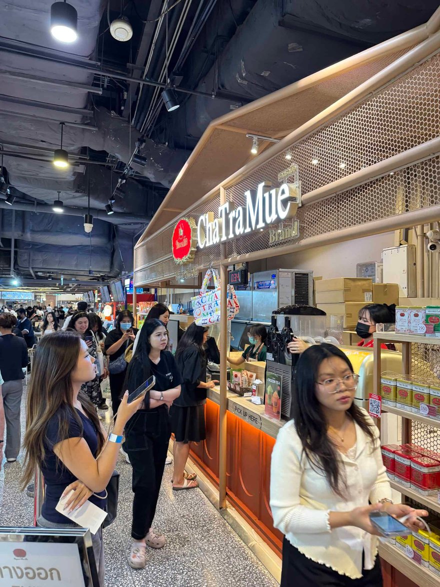 購物中心裡的 ChaTraMue 泰奶店，亮著招牌的櫃台前有人排隊等候點餐