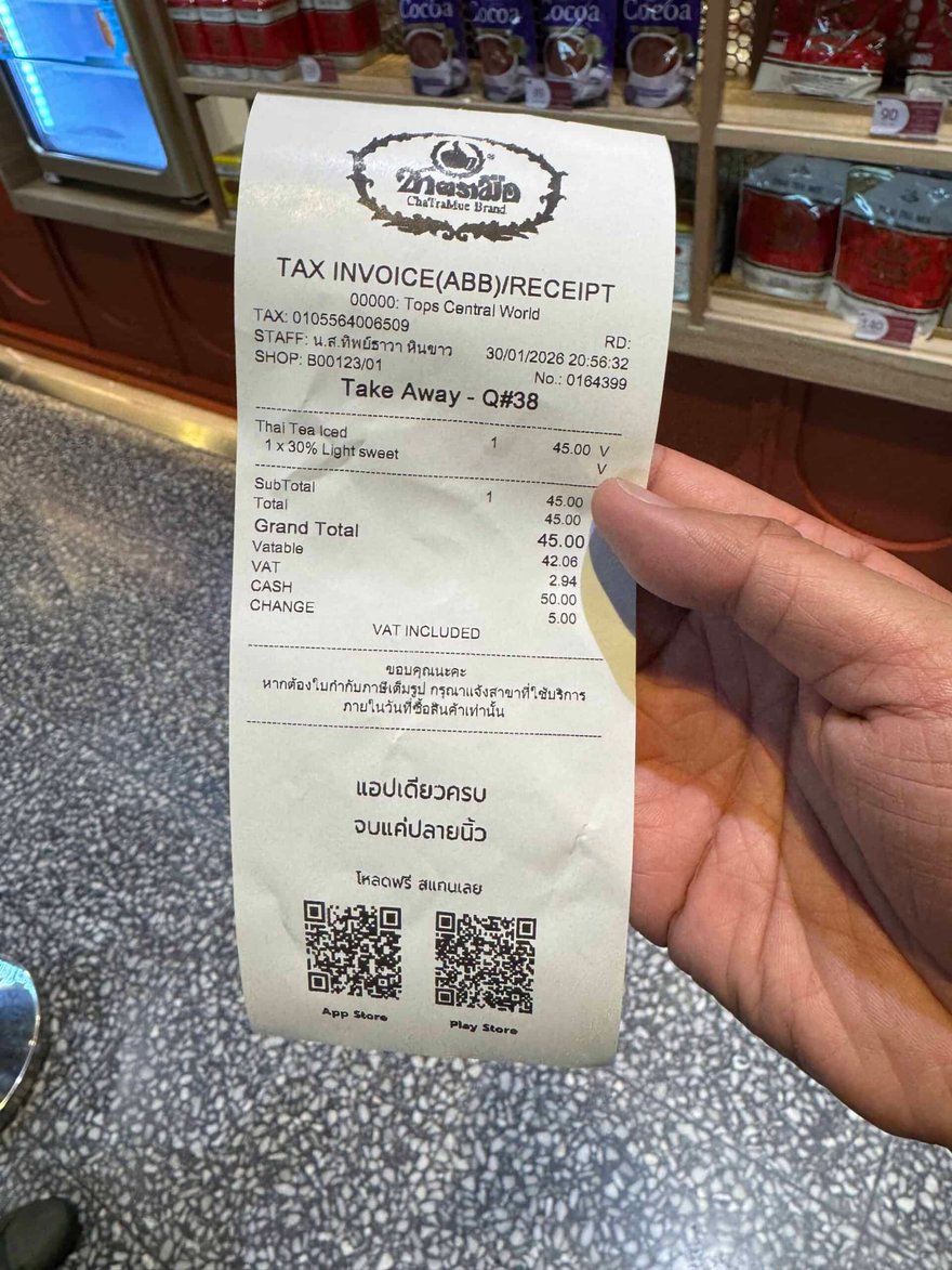 一隻手拿著 ChaTraMue 的收據，印有外帶一杯泰奶 45 泰銖，並附兩個 QR Code