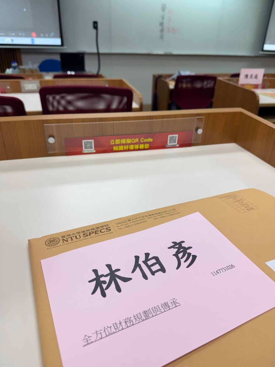 臺大進修推廣學院教室的課桌上放著黃色資料袋，上面貼著粉紅色姓名卡，寫著林伯彥與課程名稱全方位財務規劃與傳承