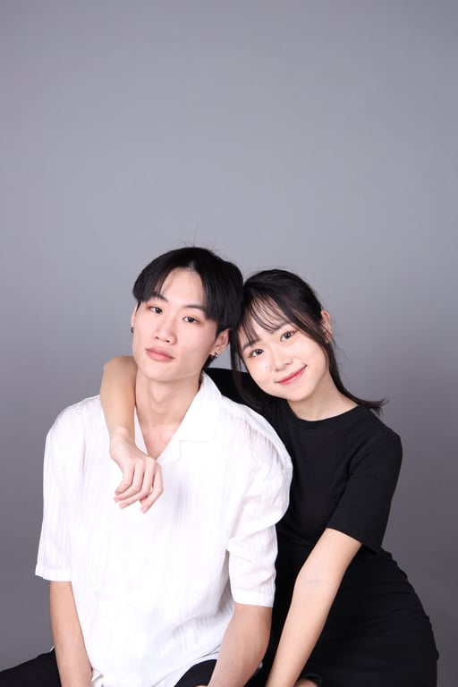 情侶寫真示範：男生穿白色上衣、手搭女生肩膀，兩人坐在灰色背景前