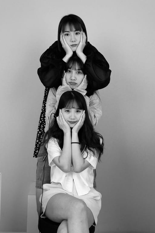 3 人姿勢「疊臉」：三位女生由上到下疊著、雙手托臉，黑白